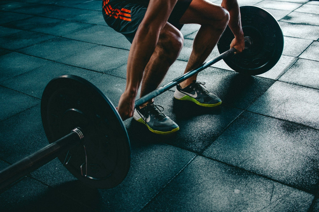lose-up of an athlete gripping an Olympic barbell for a deadlift on rubber gym flooring, highlighting technique, control, and raw power in strength training.